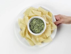 CU Woman hand entering setting down round white plate with taco chips and artichoke dip / Omaha, Nebraska, United States Stock Footage