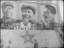 Mao Tse-tung salutes his troops while standing in jeep; Three huge portraits of Communist leaders decorate a wall; Young Chinese men carry flags and banners in a parade. News Clip