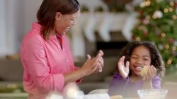 Mother and daughter ball up and pound out cookie dough on kitchen counter-top (dolly-shot) Stock Footage