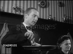 1952: NEW ORLEANS: FRENCH QUARTER: WS Restaurant headwaiter w/ tableside cooking cart, liqueurs & brandy for Crepes Suzette sauce, SOT (French) about Brennan's sauce to seated Mrs. Porto, Mr. Nutter, Mr. Porto, pan flaming, flames, flambe. Instructional Video