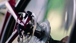 Young bike mechanic inspects spinning bicycle wheel in workshop Stock Footage