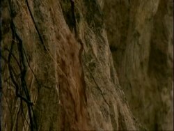 MS Muddy flood water flowing down rocky embankment, Mana Pools, Zimbabwe Stock Footage