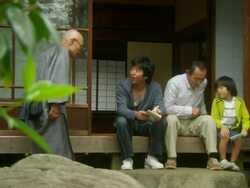MS Father, teen boy reading book and boy playing videogame sitting at entrance to house, joined by grandfather/Tokyo, Japan Stock Footage