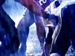 OVEREXPOSED close up zoom out football player snaps ball into play, opposing players try to tackle runner / rain Stock Footage