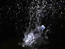 MS SLO MO Shot of Plastic bottle of water falling and splashing against black background / Calvados, Normandy, france Stock Footage