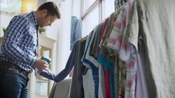 Shop owner tags prices on shirts in clothing store with tagging gun Stock Footage