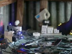Numerous power sockets and phones charging on a table top, with hands holding and unplugging one phone Stock Footage