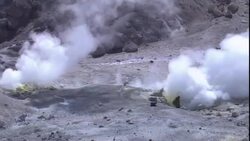A volcanologist prepares testing equipment around the crater of a smoking volcano. Stock Footage