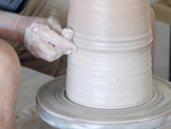 CU ceramic artist shaping wet clay of tall vessel with his hands at spinning pottery wheel  / Palm Springs, California, USA Stock Footage