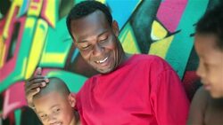 Father talks with boys leaning on graffitied wall in Rio de Janeiro Stock Footage