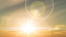 A brilliant sun creates bright coronas and halations as it rises in a golden sky. Stock Footage