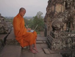 WS, PAN A Buddhist monk types on a laptop computer on top of an ancient temple in Angkor Wat / Siem Reap, Cambodia Stock Footage