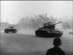 B/W 1956 PAN large Soviet tank speeds through square past camera / Hungarian uprising Stock Footage