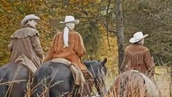 PAN Two cowboys and cowgirl riding horses on country road Stock Footage