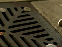 Money Down the Drain - High speed English one pound coin rolling in to road drain, mcu Stock Footage