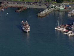 Aerial view tourists riding on an old steamer on Widermere in the Lake District / zoom out over boats in the water and docked on lake and the town of Bowness-on-Windermere / Cumbria, England Stock Footage