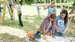 Volunteers with blueprints and carrying planks at construction site Stock Footage