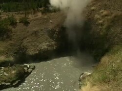 Long Shot tilt-up - Steam from a geyser rises above a microbial colored pool at Yellowstone National Park. / Wyoming, USA Stock Footage