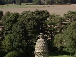 Aerial view of Dunmore Park at foot of hills / tilt down Dunmore Pineapple / Scotland Stock Footage