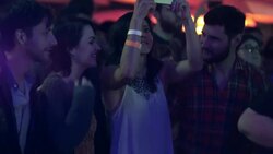 Girl takes video of rock band on smartphone as friends dance in front row Stock Footage