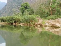MS POV SLO MO Shot of travelling boat in river bank with green trees and rocks / Mountain village near Muang Ngoi, Luang Prabang, Laos Stock Footage