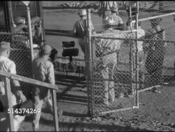 1952: HENDERSON, NEVADA: FOUNDRY: Angled MS Sign 'Titanium Metals Corporation of America' w/ arrow, HA TD Workers walking through open gate. MS Male worker wearing goggles & gloves directing material coming down shoot w/ scoop. Instructional Video