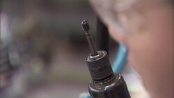 An assembly line worker places screws on the tip of an electric screwdriver. Stock Footage