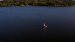 AERIAL: A lonely sailboat crossing a lake Stock Footage