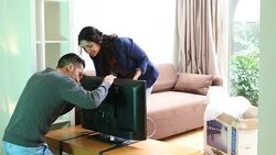 Young couple connecting cable to new television Stock Footage