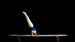 SLO MO Gymnast swinging out of handstand on parallel bars Stock Footage