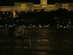 Tilt up from students on a bench to Buda Castle at night Stock Footage