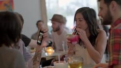 Friends drink in Austin restaurant and laugh at photo on smartphone Stock Footage