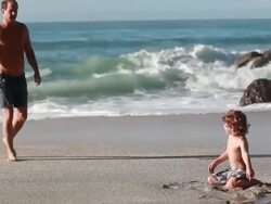 MS TS TD Man walks towards boy on beach and hands him shell  / Montezuma, Puntarenas, Costa Rica Stock Footage