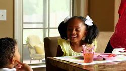 MS ZI Laughing young girl playing with infant brother while eating breakfast with family in dining room Stock Footage