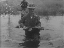 Australian soldiers trek through jungle and swamps and make contact with Viet Cong. Machine guns are fired. Vietnam War 1968 Stock Footage