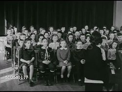1947: CLASSROOM: DRAMATIZATION: 'Carl Norcross' (now well dressed, hair slicked flat) completing science experiment, class watching. VS Children's choir sitting in chairs, singing, well groomed 'Carl Norcross' in front row, smiling at end of song. Instructional Video