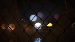 Multicolored lights twinkle through a chain link fence. Stock Footage