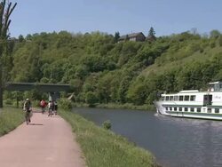 WS Boat moving on river Saar with bikers biking  / Saarburg, Saar-Valley, Rhineland-Palatinate, Germany Stock Footage