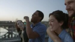 Young couples walk and talk together across pedestrian bridge at sunset Stock Footage