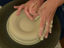 CU Shot of female potter shapes pot from lump of clay on potterwheel at pottery / Landshut, Bavaria, Germany Stock Footage