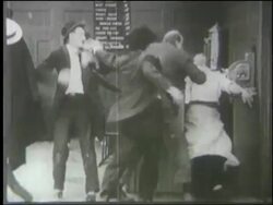 B/W 1910's group of men fighting in diner (Charlie Chaplin + Mack Swain) Stock Footage
