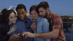 Group of friends gather around smartphone on pedestrian bridge Stock Footage