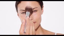 Woman applies translucent face powder to face with a brush Stock Footage