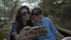 Two young women take selfie in backseat of classic convertible Ford Bronco Stock Footage