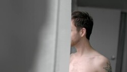 Young man stares out bedroom window drinking coffee, looks back at girlfriend in bed and smiles Stock Footage