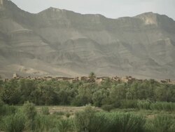 A high mountain range overlooks greenery and building tops in North Africa. Stock Footage