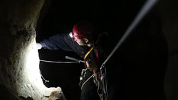 speleology explorer in a cave examining and securing a bolt on a rock 2 Stock Footage