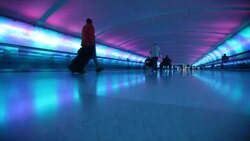 Vibrant colors line a hallway with moving sidewalks as travelers pass at Oï¿½Hare Airport in Chicago. Stock Footage