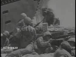 1943: BETIO, TARAWA: BEHIND US Marine firing rifle. (Low contrast, smoky) US Marines behind embankment explosion just beyond ridge. MS Marines moving injured soldier. Raising US flag on rope on coconut tree. PAN Saluting Marines. WWII. Instructional Video