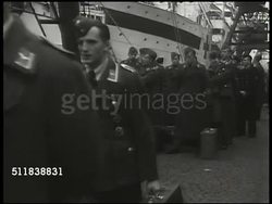 1943: NEUTRAL EXCHANGE SITE: Stern of merchant ship SS Drottningholm w/ men in uniform lining railing. VS Allied Exchange soldiers in uniform (diplomats, POWs, British, US) walking toward ramp. Volunteers serving food, coffee to waiting soldiers. WWII Instructional Video
